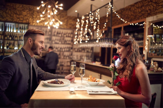 Couple having a romantic dinner with Champagne and a red rose