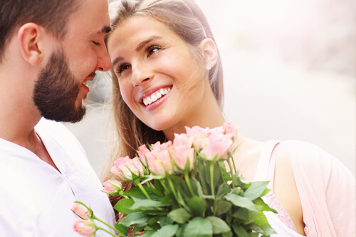 Couple smiling holding pink roses