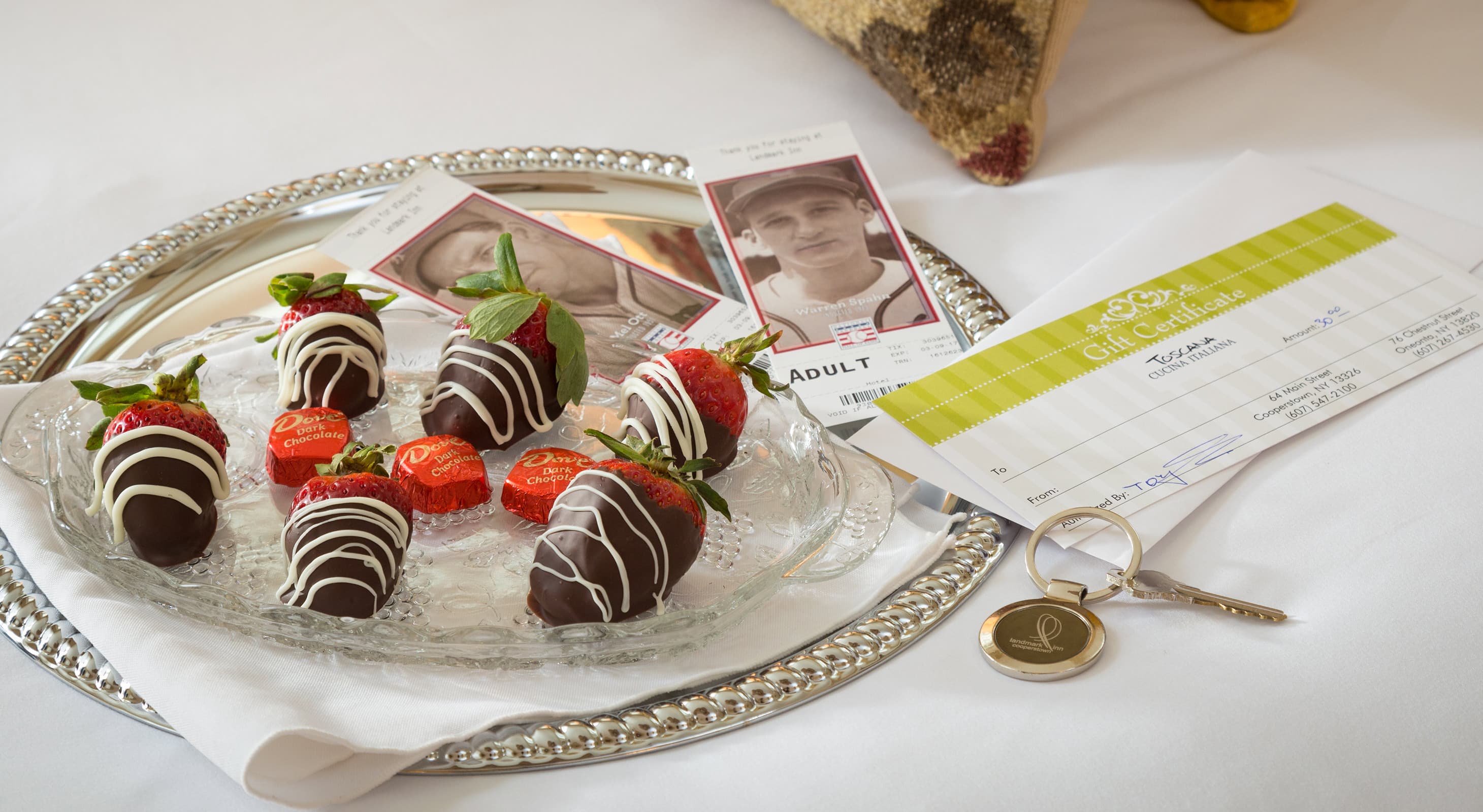 chocolate covered strawberries on a bed with tickets to the Baseball Hall of Fame