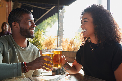 Couple with glasses of beer smiling and doing cheers