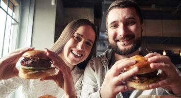 Couple smiling and holding juicy burgers in their hands