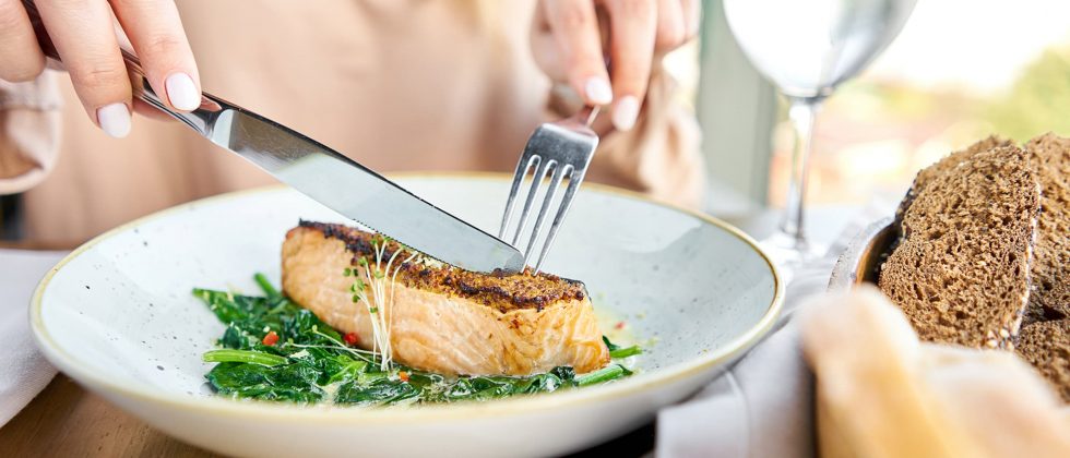 woman cutting a salmon steak at a restaurant