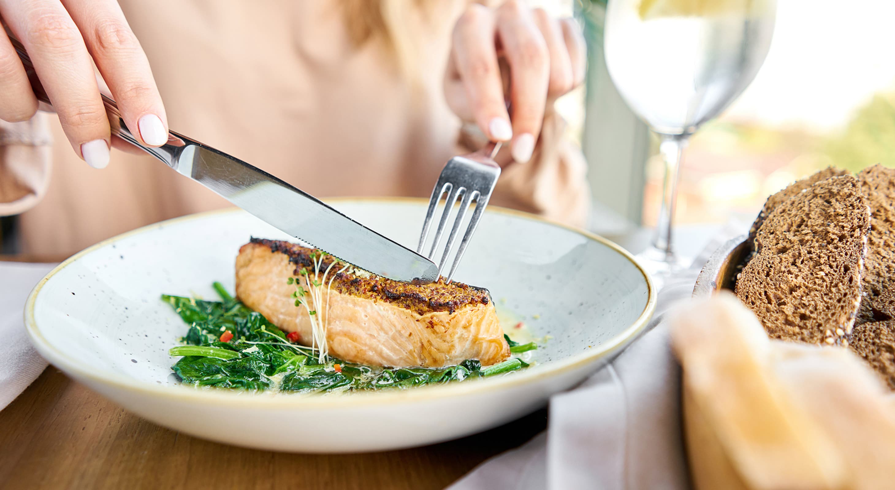 woman cutting a salmon steak at a restaurant