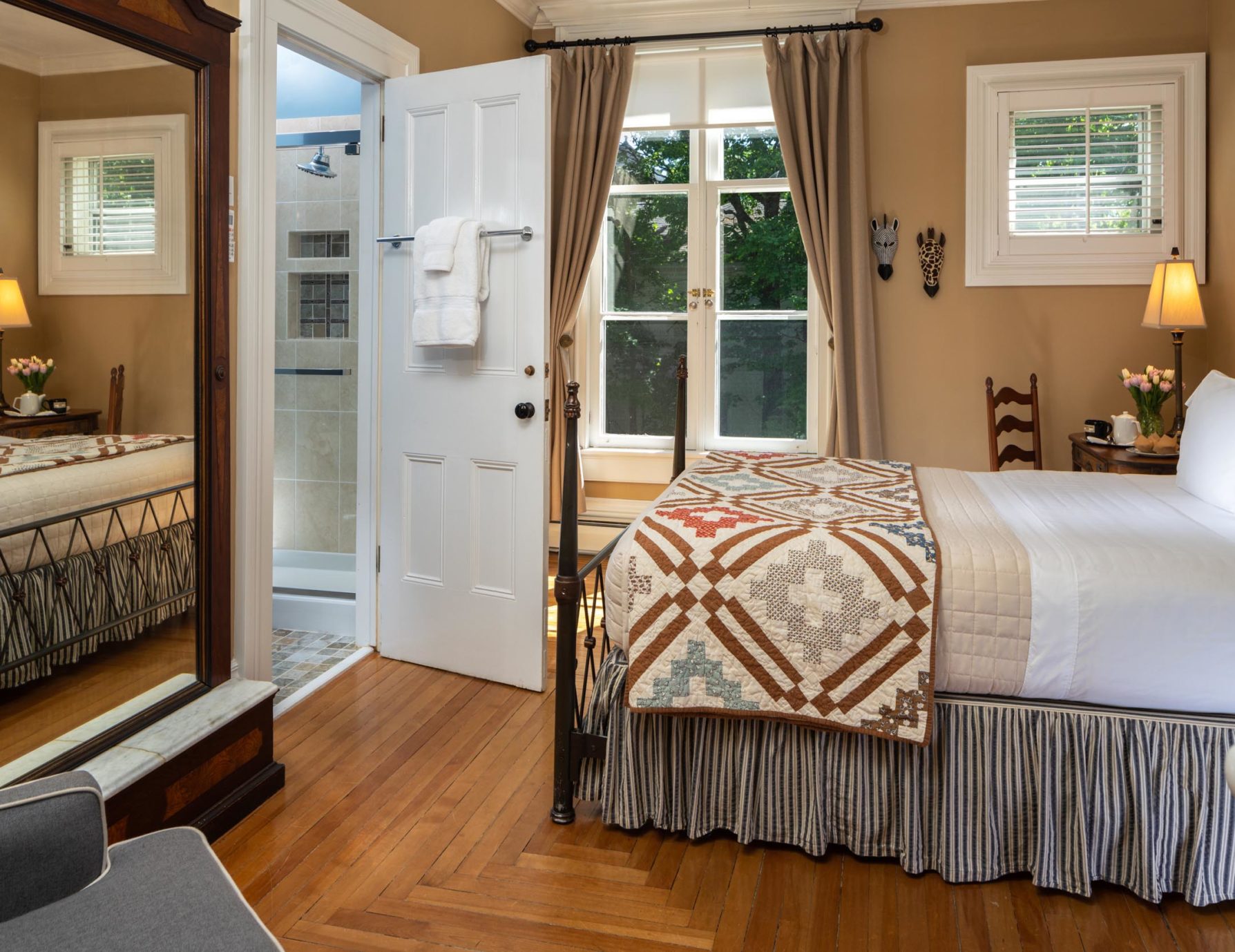 Wide shot of bed and mirror in the Hemingway Room at a Cooperstown Inn