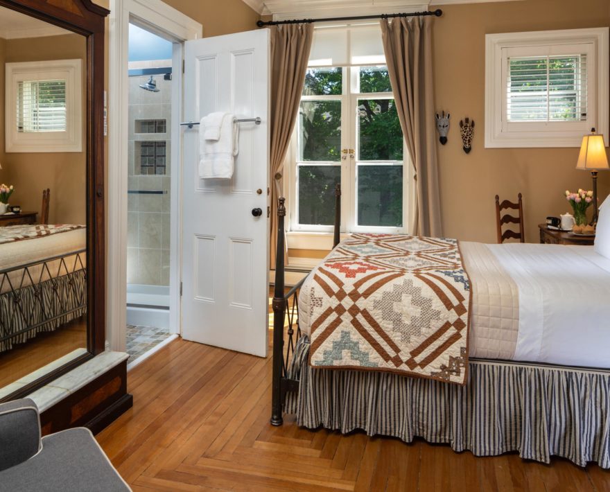 Wide shot of bed and mirror in the Hemingway Room at a Cooperstown Inn