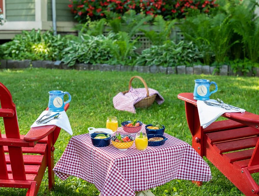 Breakfast waffles on table between Adirondack chairs with signature Landmark Inn mugs